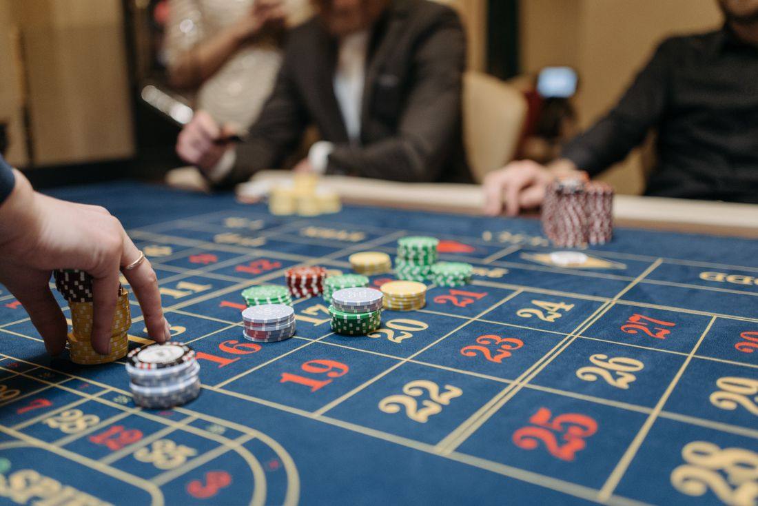 Tangan menata chip di meja roulette (foto: Pexels)